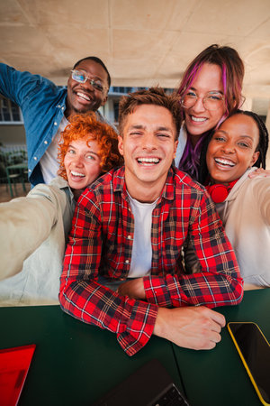 Vertical. cheerful group of diverse teenage students taking a selfie together, smiling brightly at the camera, enjoying friendship and fun momentsの写真素材