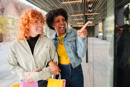 Excited girls enjoying a joyful shopping experience while pointing at something interesting togetherの写真素材