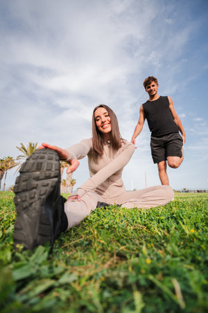 Active couple enjoying a joyful stretching routine together while exercising on a sunny day outdoorsの写真素材