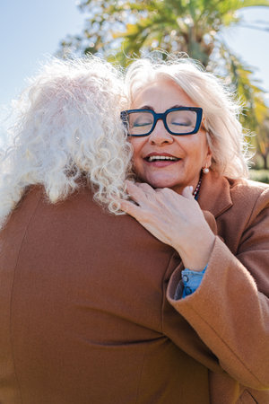 Joyful embrace of two elderly friends celebrating their long-lasting friendship with heartfelt smiles and genuine affection in a moment of warmth andの写真素材