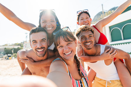 Five joyful friends capturing a memorable selfie during a sunny summer day at the beautiful beachの写真素材