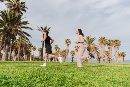 Active couple jogging together in a sunny park while enjoying their fitness routine and staying healthyの写真素材