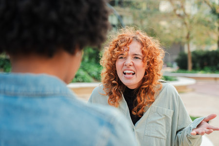Two women engaged in a heated argument showcasing intense emotions and expressive gestures of frustrationの写真素材