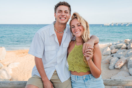 Joyful couple enjoying a sunny beach day together while smiling and posing for a cheerful photographの写真素材