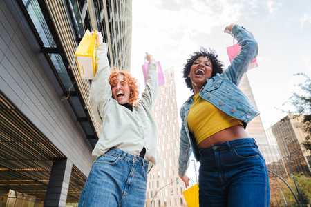 Joyful friends celebrating their shopping experience with colorful bags and cheerful expressions in the cityの写真素材