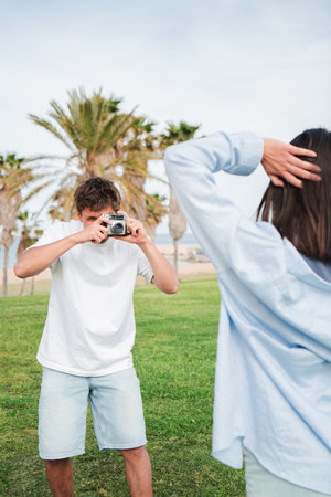 Young couple capturing joyful moments together while posing for photographs with a vintage cameraの写真素材