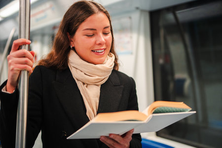 Young woman enjoys a captivating book while reading on public transport during her daily commute in...