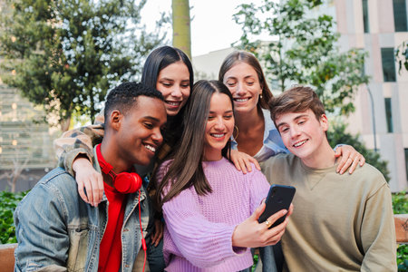 Joyful group of friends enjoying a fun moment together while watching something on a smartphone