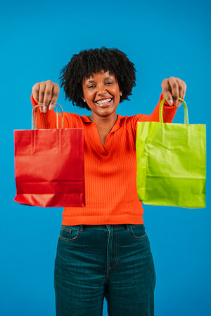 Excited woman joyfully showcasing colorful shopping bags with a bright smile while celebrating her successful shopping experience in a lively andの写真素材