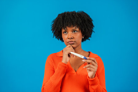 Thoughtful woman contemplating her future while holding a pregnancy test, reflecting on life...