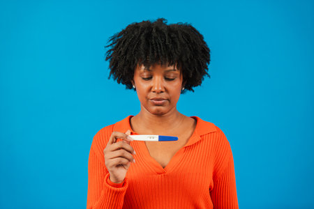 Thoughtful woman examining pregnancy test with mixed emotions as she contemplates the future while reflecting on her current life situation and theの写真素材