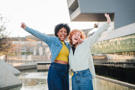 Joyful friends celebrating together with arms raised in cheerful enthusiasm and pure happiness outdoorsの写真素材