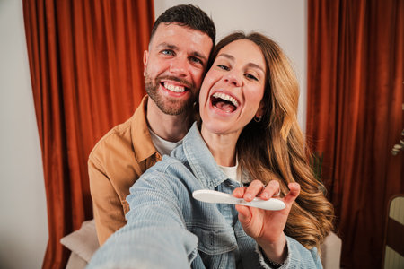 Excited couple happily celebrating pregnancy news while taking a joyful selfie with a test
