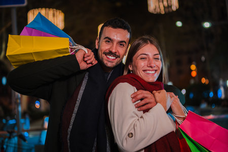 Joyful Couple Enjoying Shopping Together with Colorful Bags at Night, Smiling and Celebrating Their Purchases in a Romantic and Fun Atmosphere, Fullの写真素材