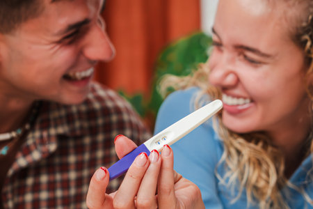 Excited couple sharing joyful moment while looking at pregnancy test results with happy expressionsの写真素材