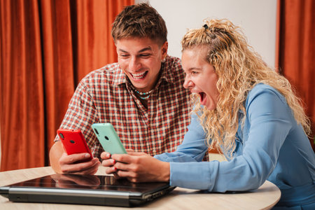 Two friends share a joyful moment while engaging with their smartphones in a fun and lively manner