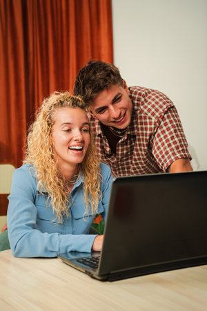 Joyful couple sharing laughter while browsing on a laptop, enjoying a delightful moment togetherの写真素材