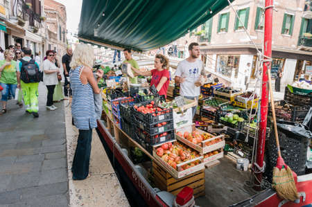 Venice, Italy - May 28th 2018. Local traders sell goods on floating market stall on a boat in Venice. Locals and tourists buy, support local economyのeditorial素材