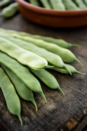 A bunch of string beans lay on a dark wooden boardの写真素材