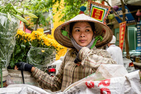 Hanoi, Vietnam - March 26th 2013. A young woman looks out in her flowers market stall in the streets of Hanoi, Vietnamのeditorial素材
