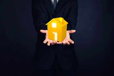 businessman offering a house holding a house in his handsの写真素材