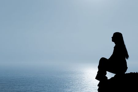 Meditating woman silhouette against seascape.の写真素材