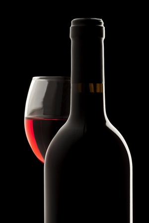 Elegant red wine bottle and wine glass in a black backgroundの写真素材