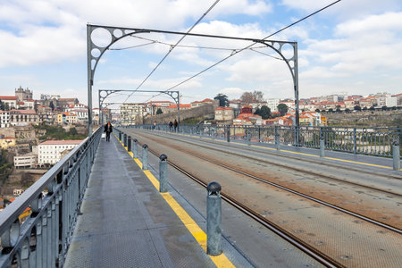 Subway railway tracks and electric cables on the superior deck of the Dom Luis I bridge connecting Vila Nova de Gaia to the city of Porto, seen in the background, over the Douro Riverのeditorial素材