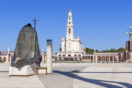 Sanctuary of Fatima, Portugal, March 07, 2015 - Statue of Pope John Paul II with Our Lady of the Rosary Basilica in background. Fatima is one of the most important pilgrimage locations for Catholicsのeditorial素材