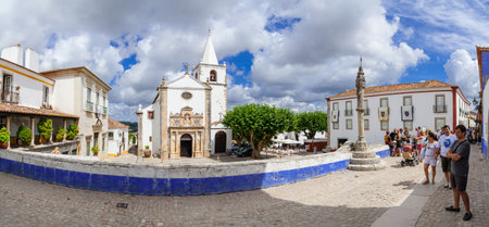 Obidos, Portugal - July, 2015: Santa Maria Church and Town Pillory seen from Direita Street. Obidos is a medieval town inside walls, and very popular among tourists.のeditorial素材