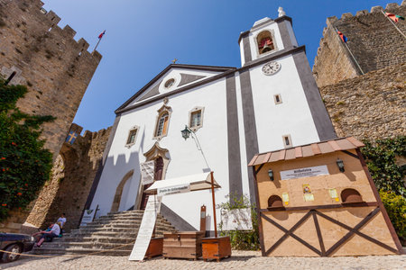 Obidos, Portugal - August, 2015: Santiago Church and Albarra Castle Tower. Obidos is a medieval town still inside castle walls, and very popular among tourists.のeditorial素材