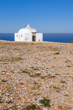 The remote Ermida da Memoria Memory Hermitage of the Nossa Senhora do Cabo Sanctuary, built on the edge of a cliff on Espichel Cape, with the Atlantic Ocean in background. Sesimbra, Portugal.の写真素材