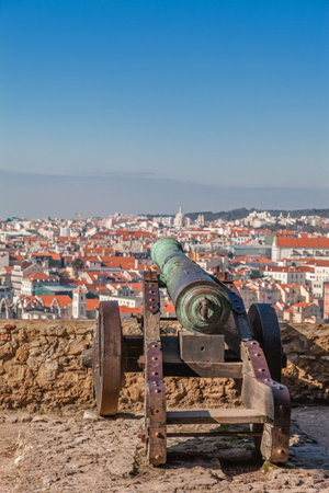 Lisbon, Portugal. Old bronze cannon in Sao Jorge aka Saint George Castle and a view of Lisbon Baixa District rooftops.のeditorial素材