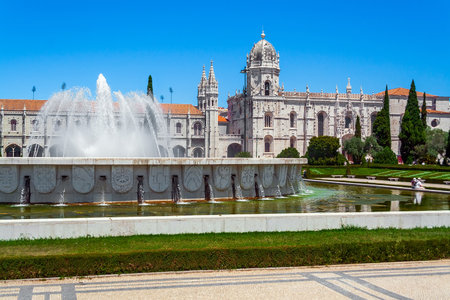 Lisbon, Portugal. Jeronimos Monastery or Abbey aka Santa Maria de Belem seen from Jardim da Praca do Imperio Garden and Square. Fountain with water jets sprayのeditorial素材