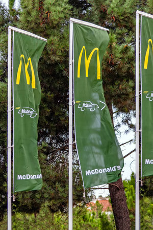 Coina, Portugal - October 23, 2019: McDonaldâs flags with Golden Arches and the McDrive drive thru service symbol at the entrance of a McDonalds restaurantのeditorial素材
