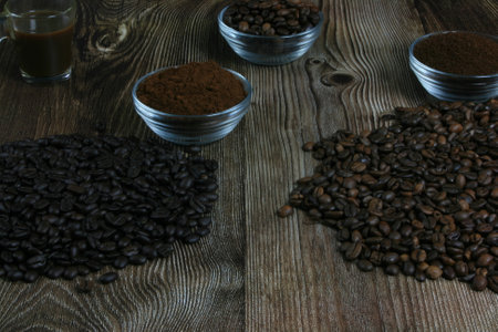 Robes of roasted coffee and intense toast in heaps, accompanied by bowl with ground coffee on a wooden tableの写真素材
