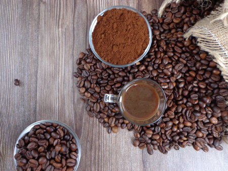 Robes of roasted coffee and intense toast in heaps, accompanied by bowl with ground coffee on a wooden tableの写真素材