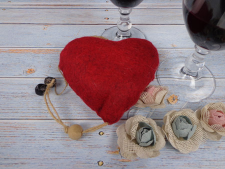 Romantic scene of two glasses of red wine and a red heart on a vintage wooden background, with space to place textの写真素材