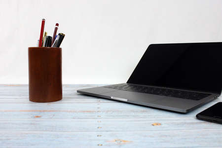 Top view of a computer accompanied by a tablet, a mobile phone and office supplies on vintage wooden backgroundの写真素材