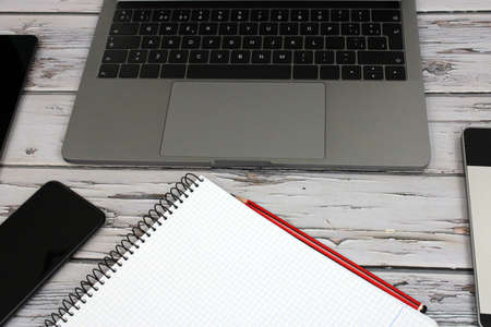 Top view of a computer accompanied by a tablet, a mobile phone and office supplies on vintage wooden backgroundの写真素材