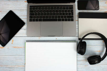 Top view of a computer accompanied by a tablet, a mobile phone and office supplies on vintage wooden backgroundの写真素材