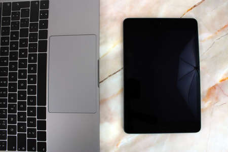 Top view of a computer accompanied by a tablet, a mobile phone and office supplies on marble backgroundの写真素材