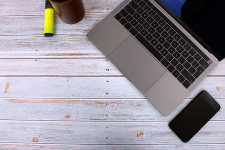 Top view of a computer accompanied by a tablet, a mobile phone and office supplies on vintage wooden backgroundの写真素材
