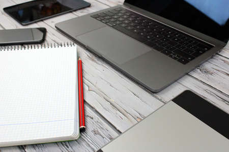 Top view of a computer accompanied by a tablet, a mobile phone and office supplies on vintage wooden backgroundの写真素材