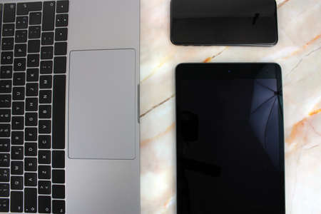 Top view of a computer accompanied by a tablet, a mobile phone and office supplies on marble backgroundの写真素材