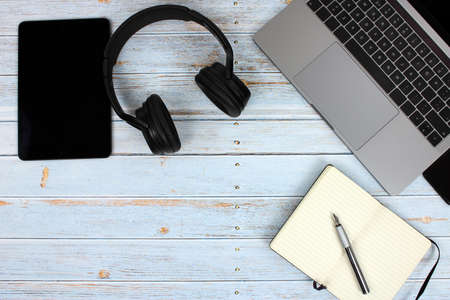 Top view of a computer accompanied by a tablet, a mobile phone and office supplies on vintage wooden backgroundの写真素材