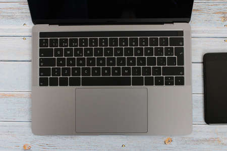 Top view of a computer accompanied by a tablet, a mobile phone and office supplies on vintage wooden backgroundの写真素材