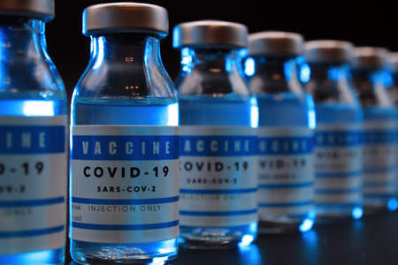 Covid-19 vaccine vials lined up on a black background