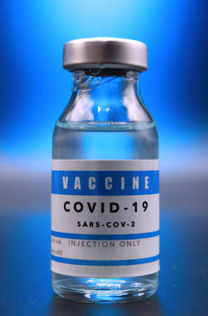 Covid-19 vaccine vial under a blue flashの写真素材