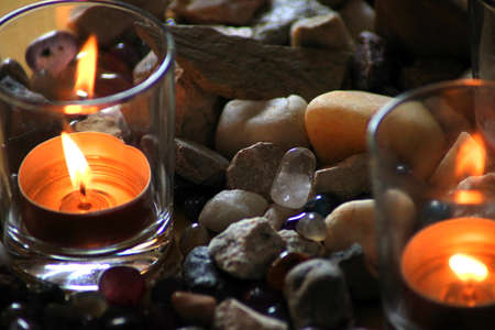 Burning candles in a glass jar and stones on a stone backgroundの写真素材